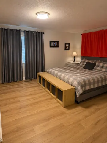 Room featuring wood-finish flooring, a flush-mount ceiling light fixture, and a window with blinds