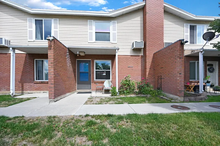 Townhome exterior featuring tan horizontal siding and red brick accents
