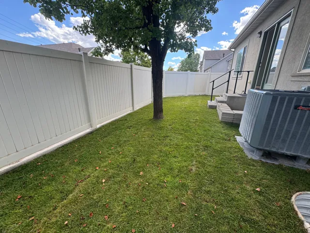 Lawn area bordered by white privacy fencing