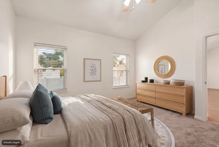 Primary bedroom with vaulted ceiling and new carpet (virtually staged)