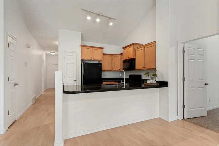 Kitchen featuring wood cabinetry, black appliances, a black granite countertop