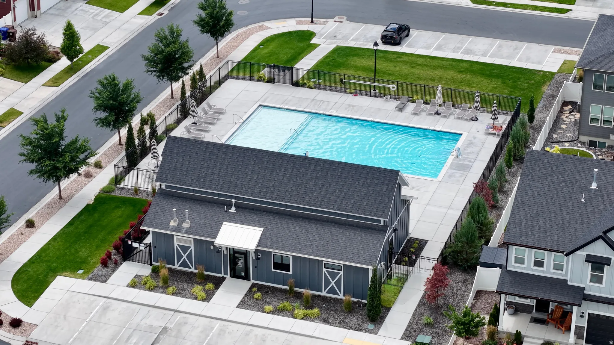 Outdoor swimming pool with surrounding patio, lounge chairs, and umbrella seating