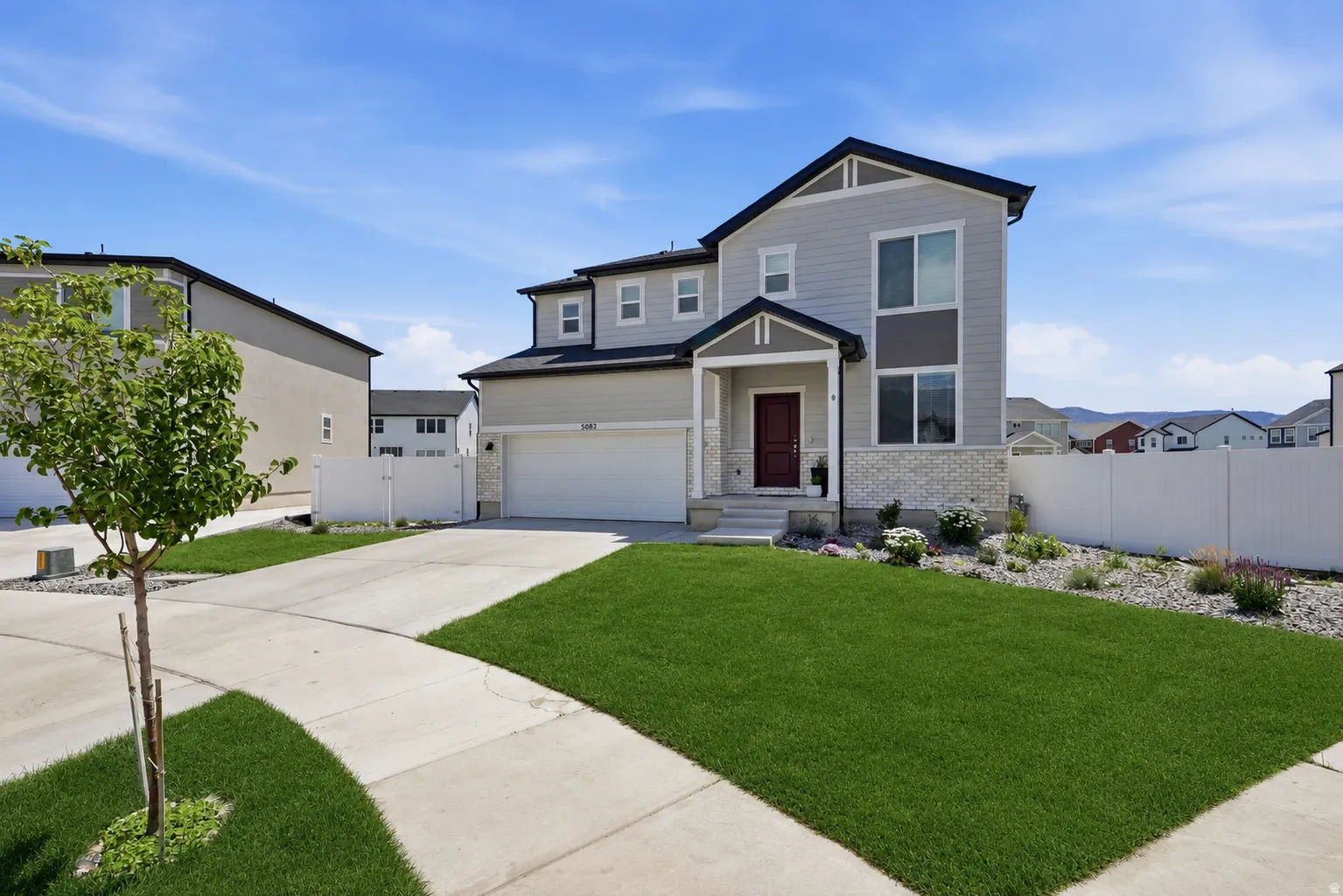Contemporary two-story residence featuring light gray siding and dark trim.