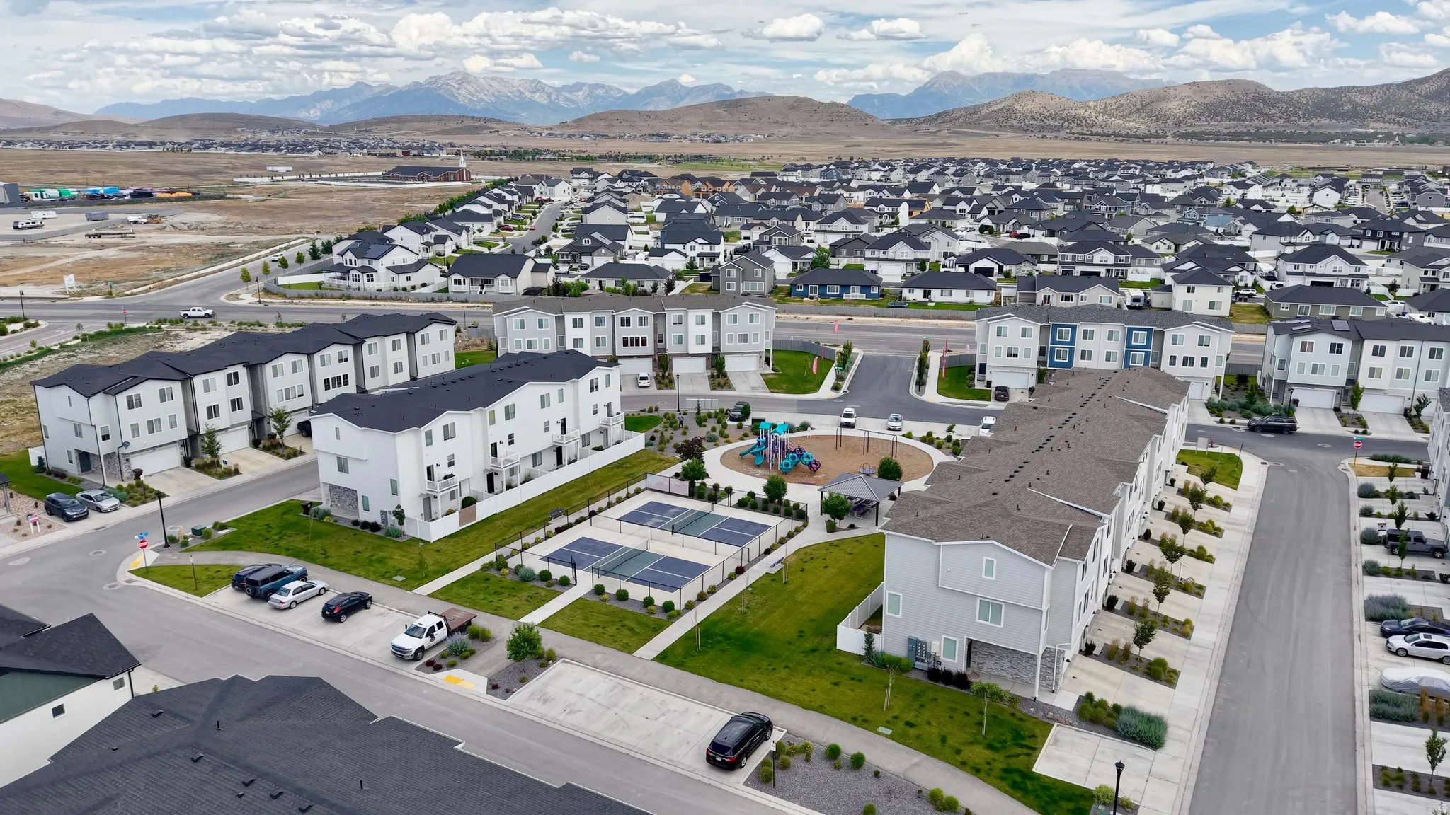 Expansive community featuring multi-story townhomes with dark gray roofs and light-toned siding