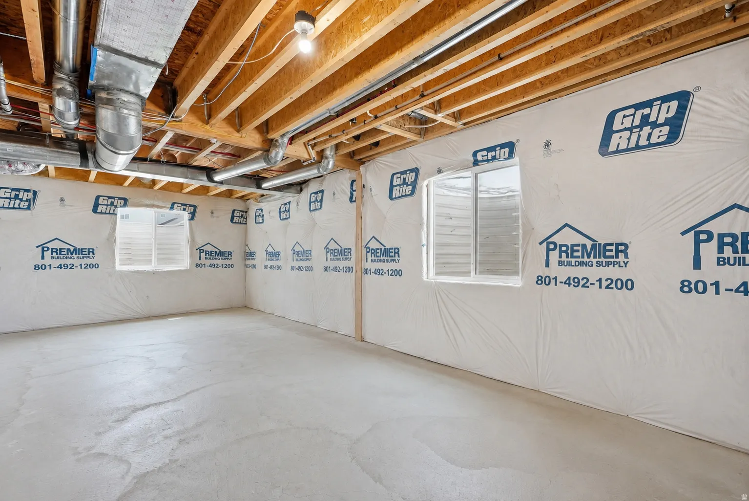 Unfinished basement featuring exposed wood joists, overhead ductwork, and concrete flooring