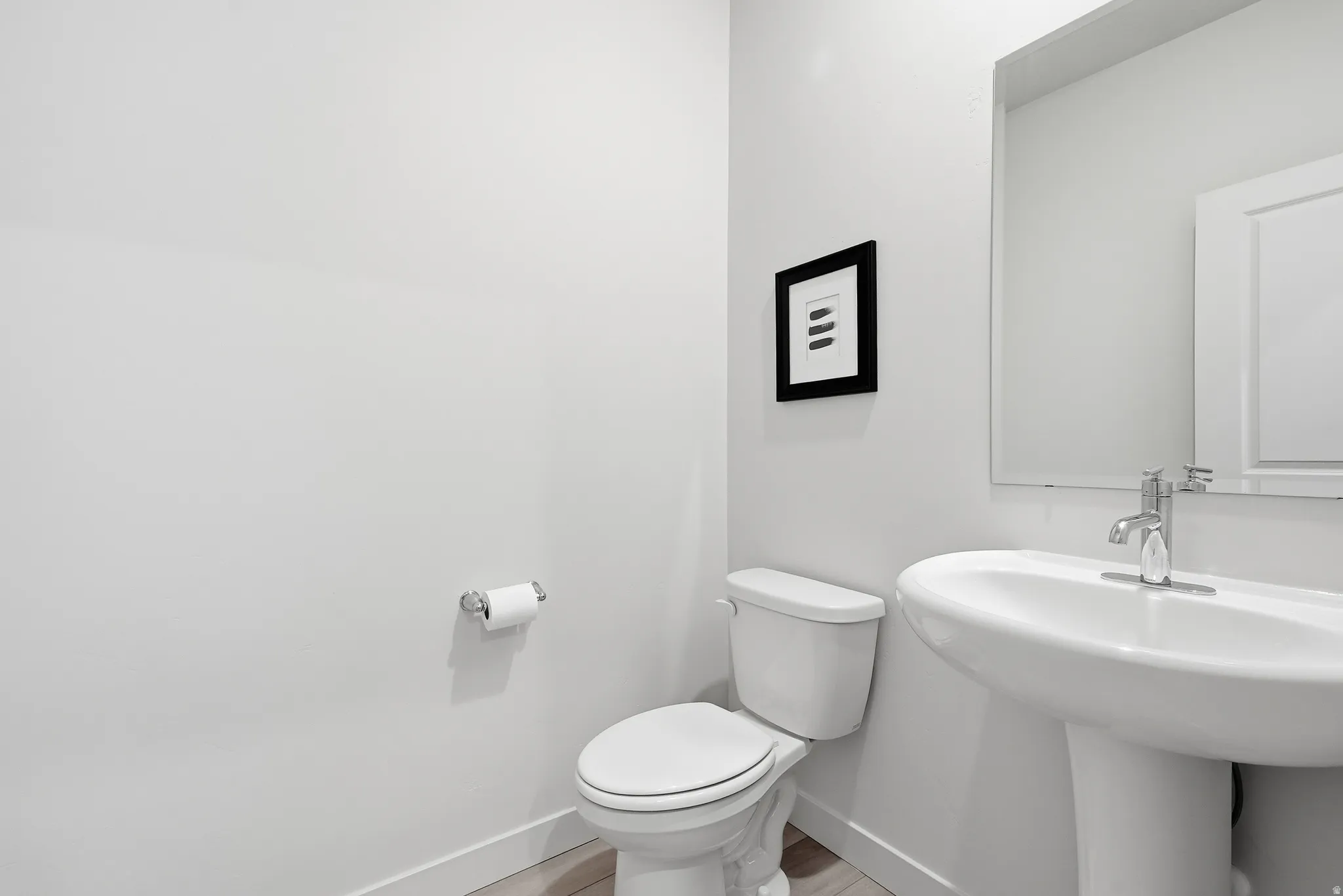 Pedestal sink with chrome faucet and polished mirror