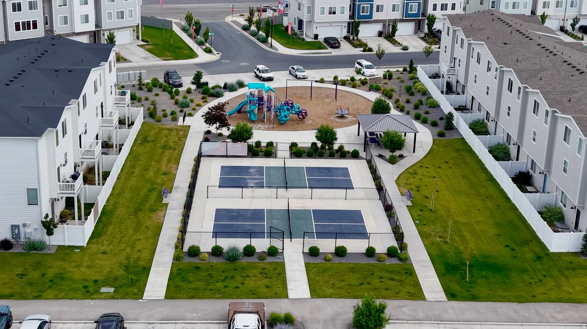 Community amenities including two fenced pickleball courts, a covered pavilion, and a central playground with a soft-surface area