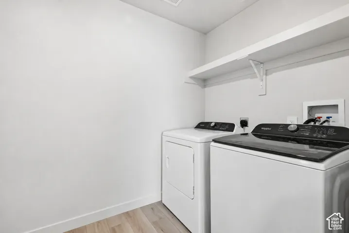 Dedicated laundry area featuring a white wall shelf, wood-finish flooring, and light-toned walls