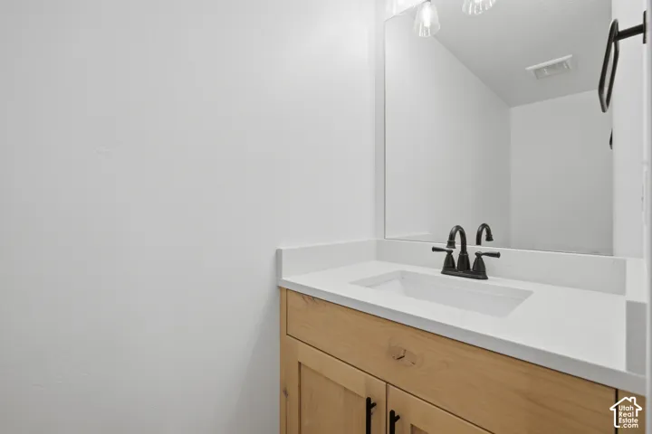 Wood-finish vanity with integrated sink, white countertop, and matte black faucet