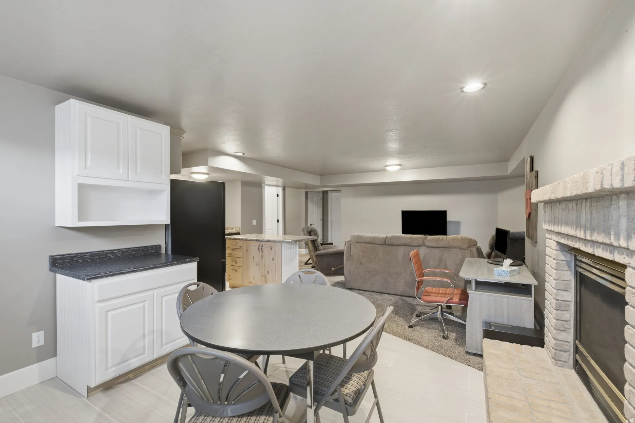 Open-concept living area featuring a stone-clad fireplace and light wood-finish flooring