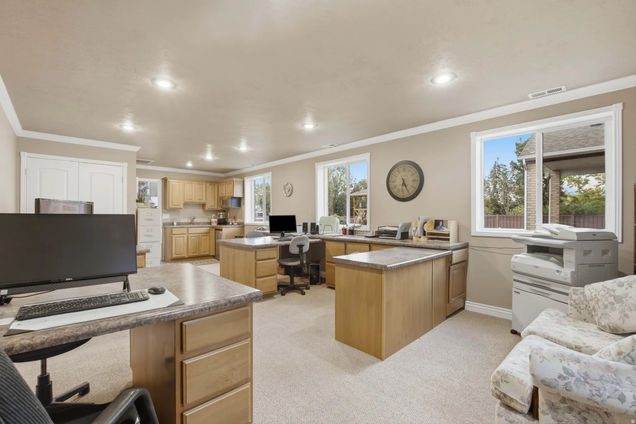 Spacious room featuring multiple built-in desks, a full kitchen with light wood cabinetry, and recessed lighting