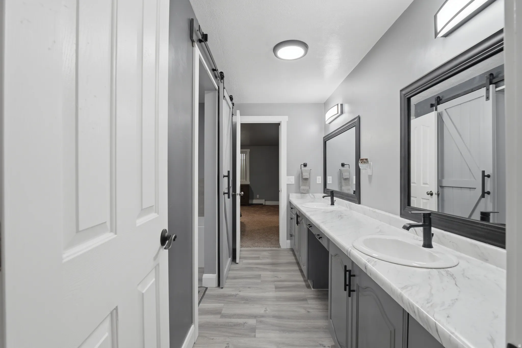 Dual vanity with integrated sinks, white countertops, gray cabinetry, and matte black fixtures