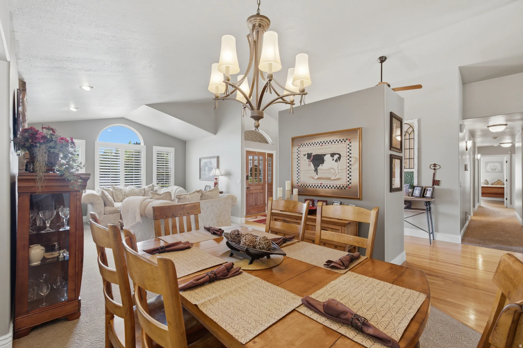 Formal dining space featuring a polished wood table, chandelier lighting, and a partial wall with decorative art