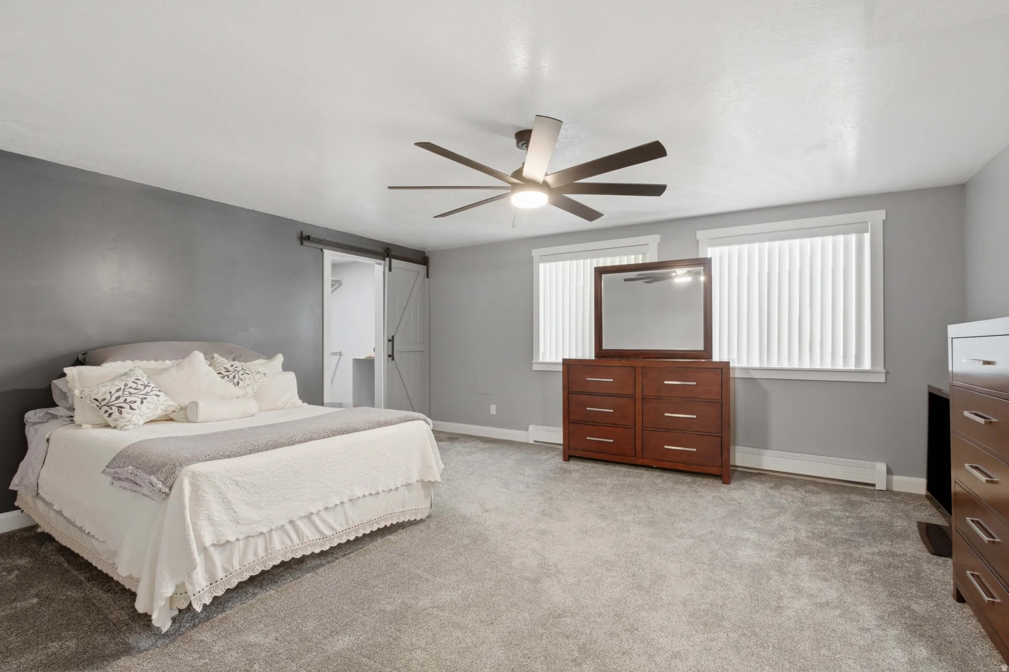 Spacious room featuring gray wall paint, light gray carpeting, and a ceiling fan with integrated lighting
