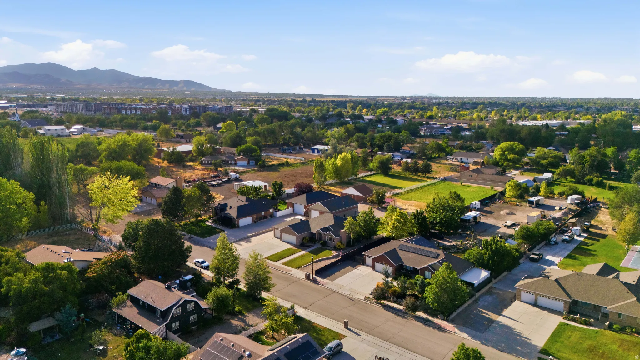 Residential neighborhood featuring a paved street, mature trees, and individual properties with pitched roofs