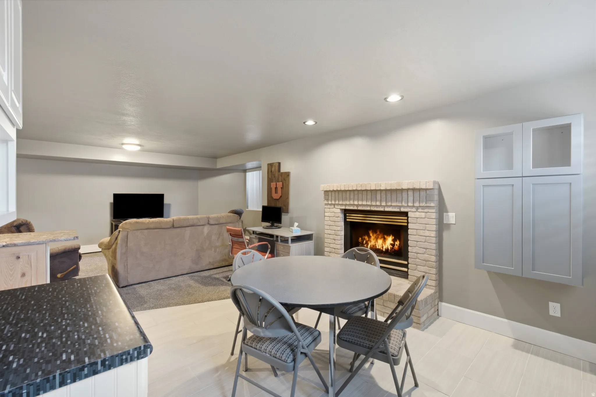 Open-concept living space featuring a brick fireplace, recessed lighting, and a blend of carpeted and wood-finish flooring