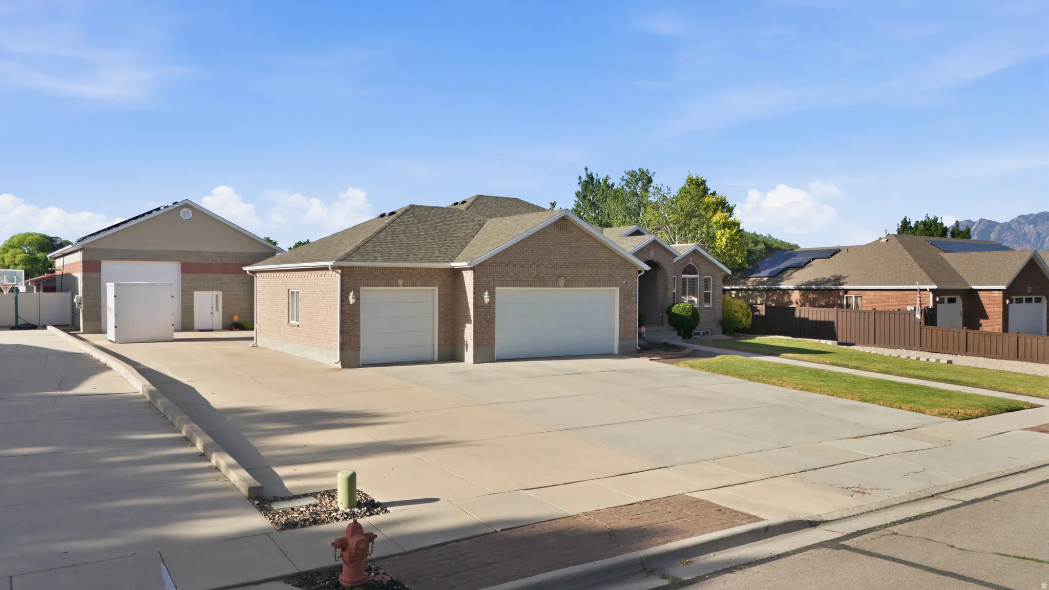 Brick residence featuring a dual two-car garage and an additional detached garage with a tall overhead door
