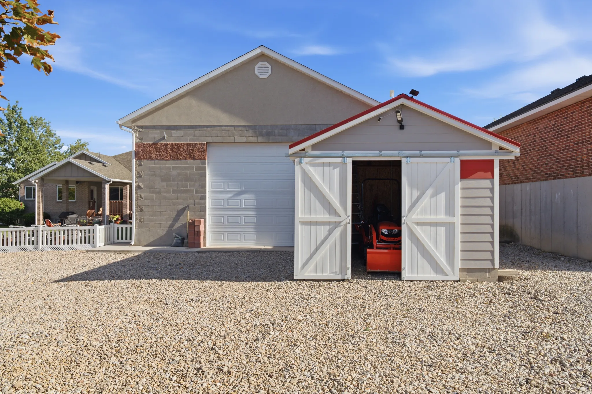 Spacious gravel driveway offering ample parking and access to a large attached garage with a white panel door