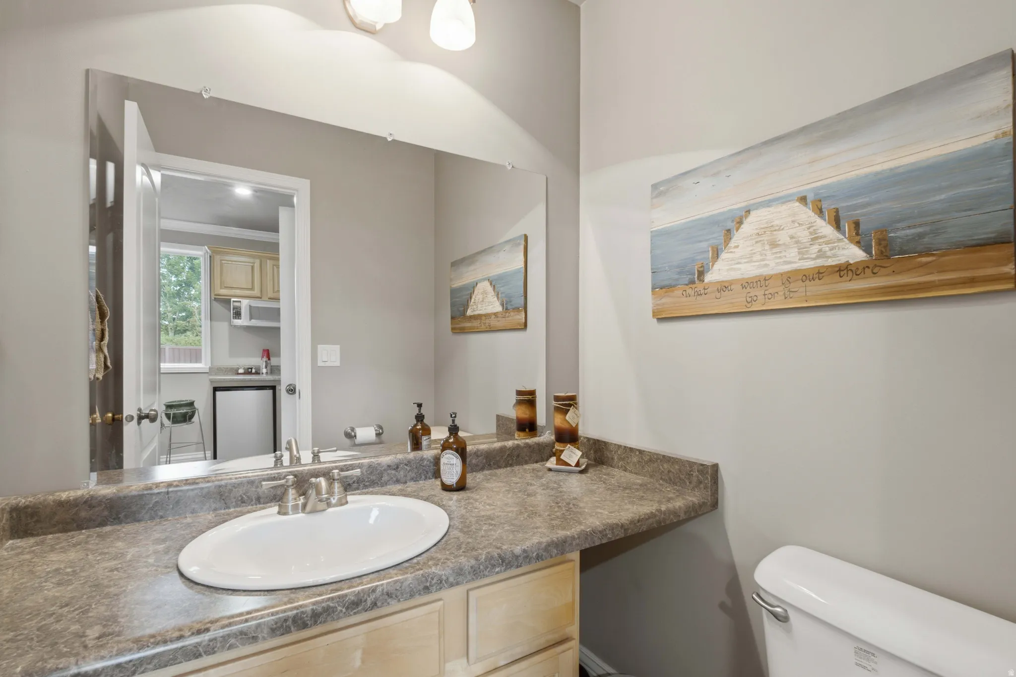 Bathroom vanity featuring an oval sink with brushed nickel hardware, a speckled countertop, and light wood cabinetry
