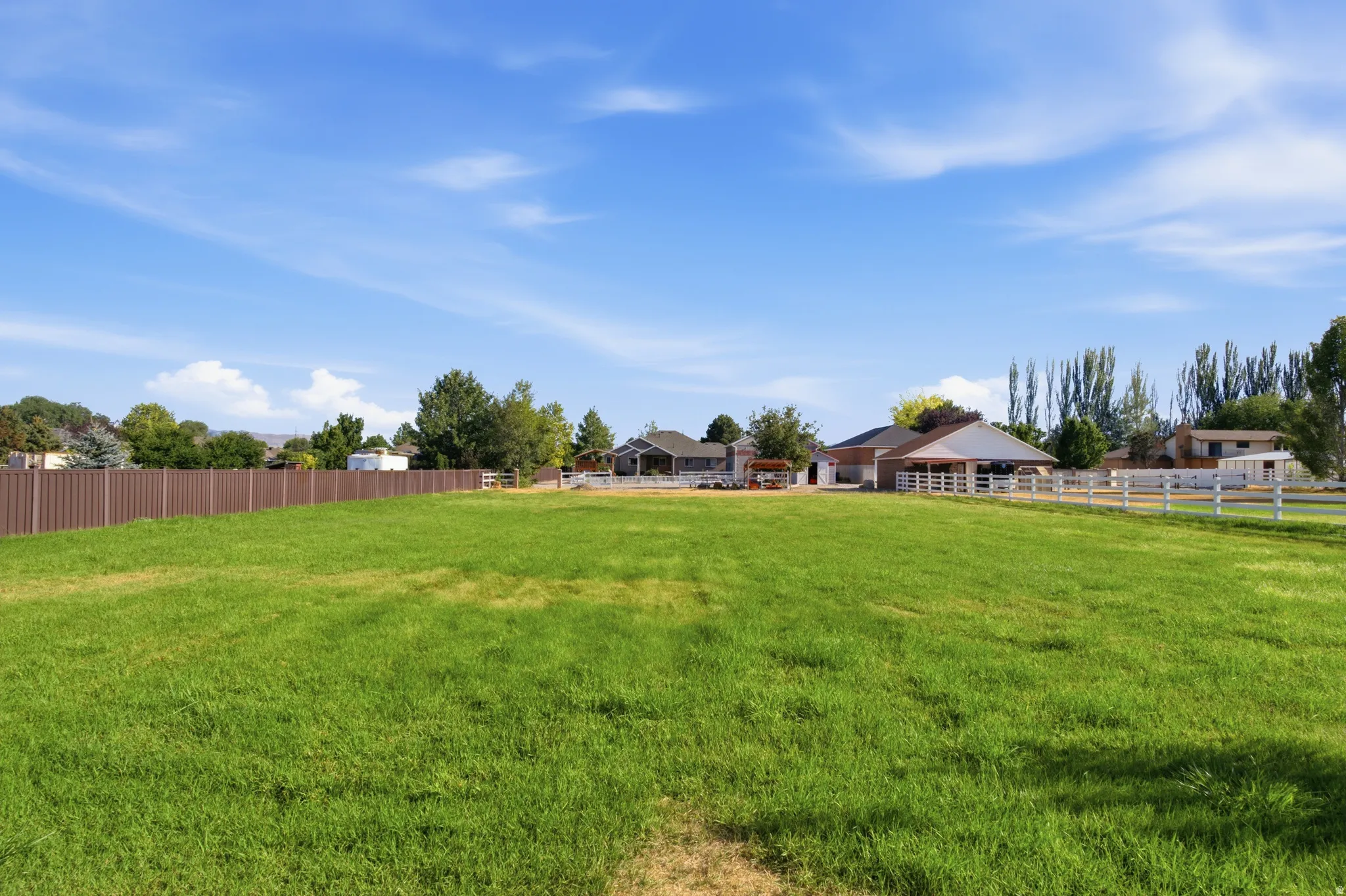 Expansive green lawn with a brown privacy fence