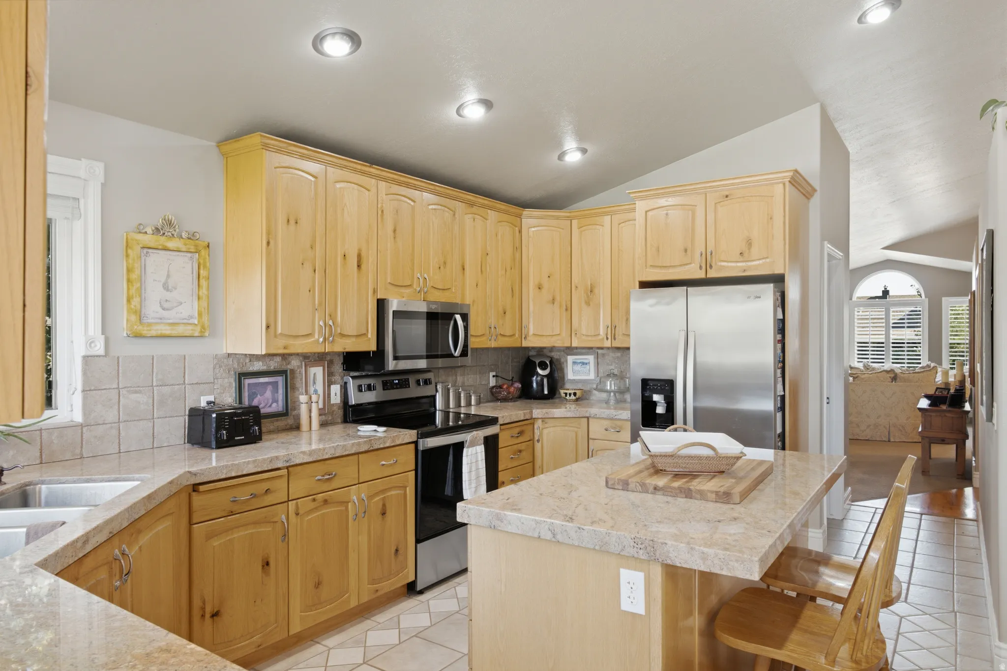 Kitchen featuring light wood cabinetry, stone-finish countertops, stainless steel appliances, and recessed lighting
