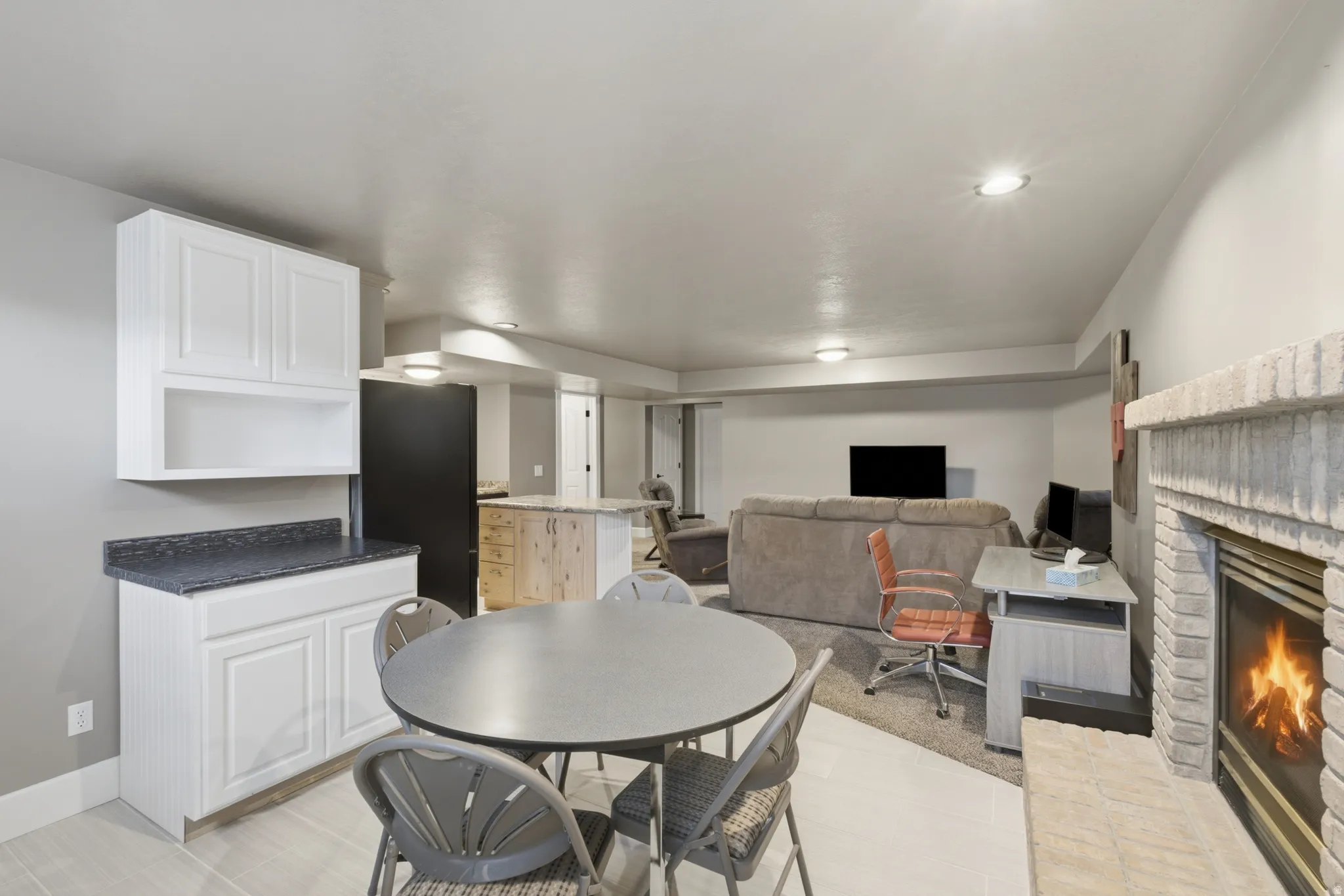 Open-concept living space featuring a white brick fireplace, recessed lighting, and light-toned flooring