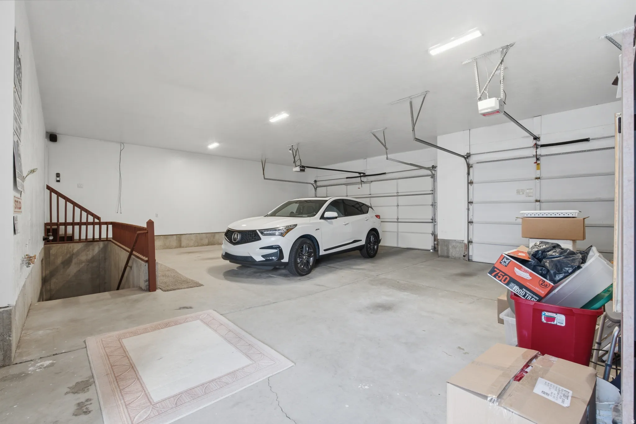 Spacious garage with concrete flooring, two overhead doors, and overhead lighting