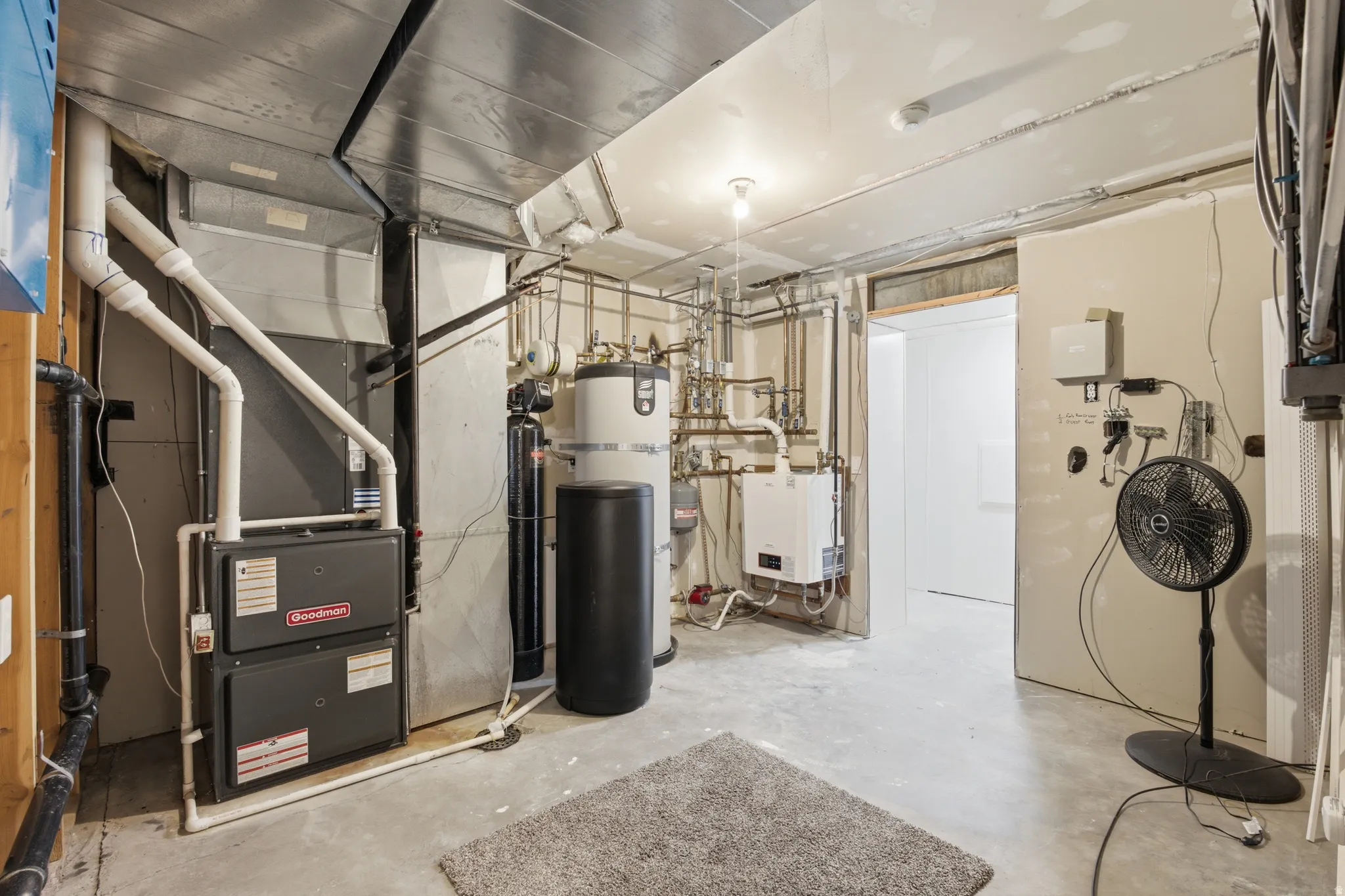 Utility area featuring a furnace, water heater, and various plumbing and electrical systems