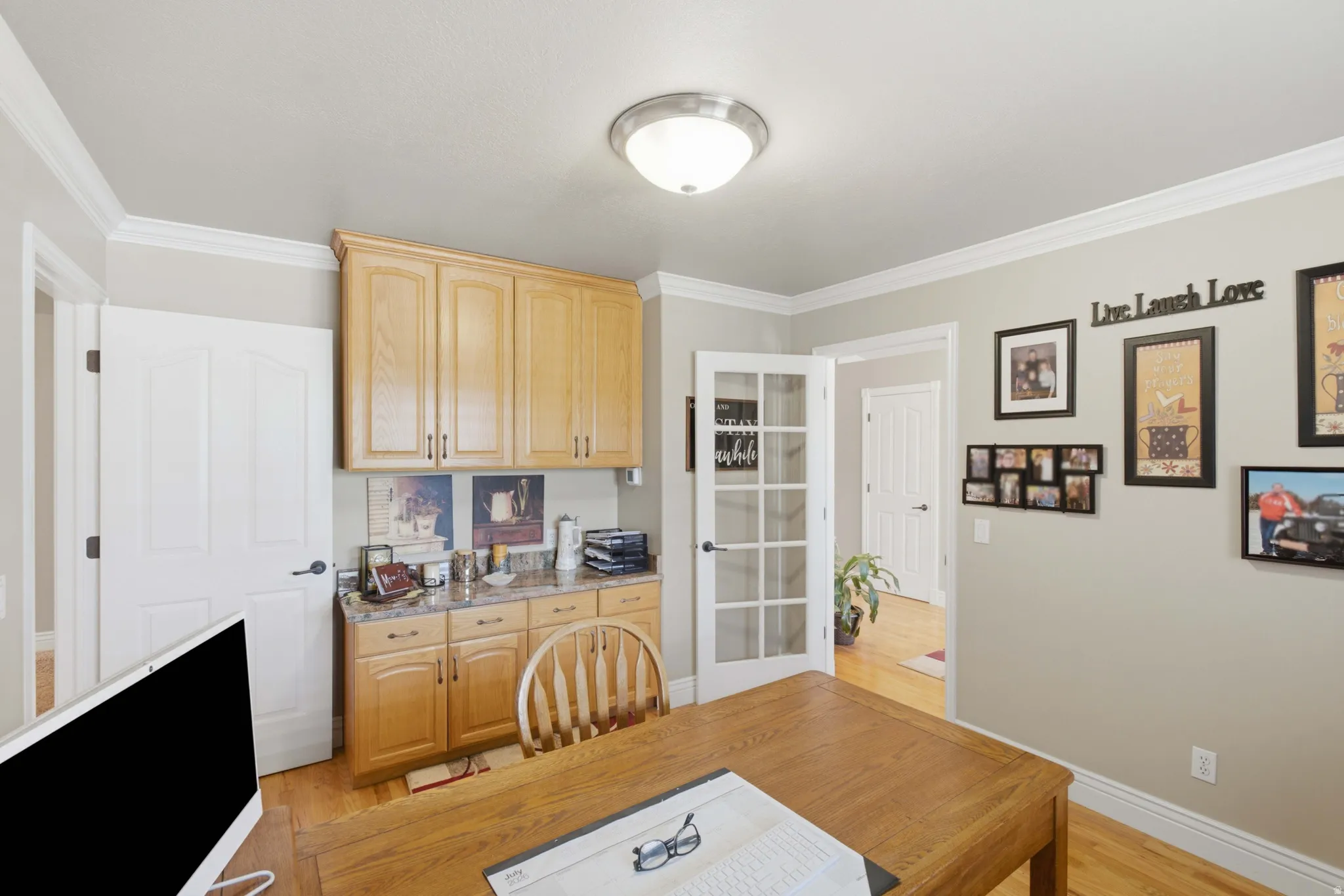 Room featuring a built-in cabinetry system with light wood-finish doors and a stone-look countertop
