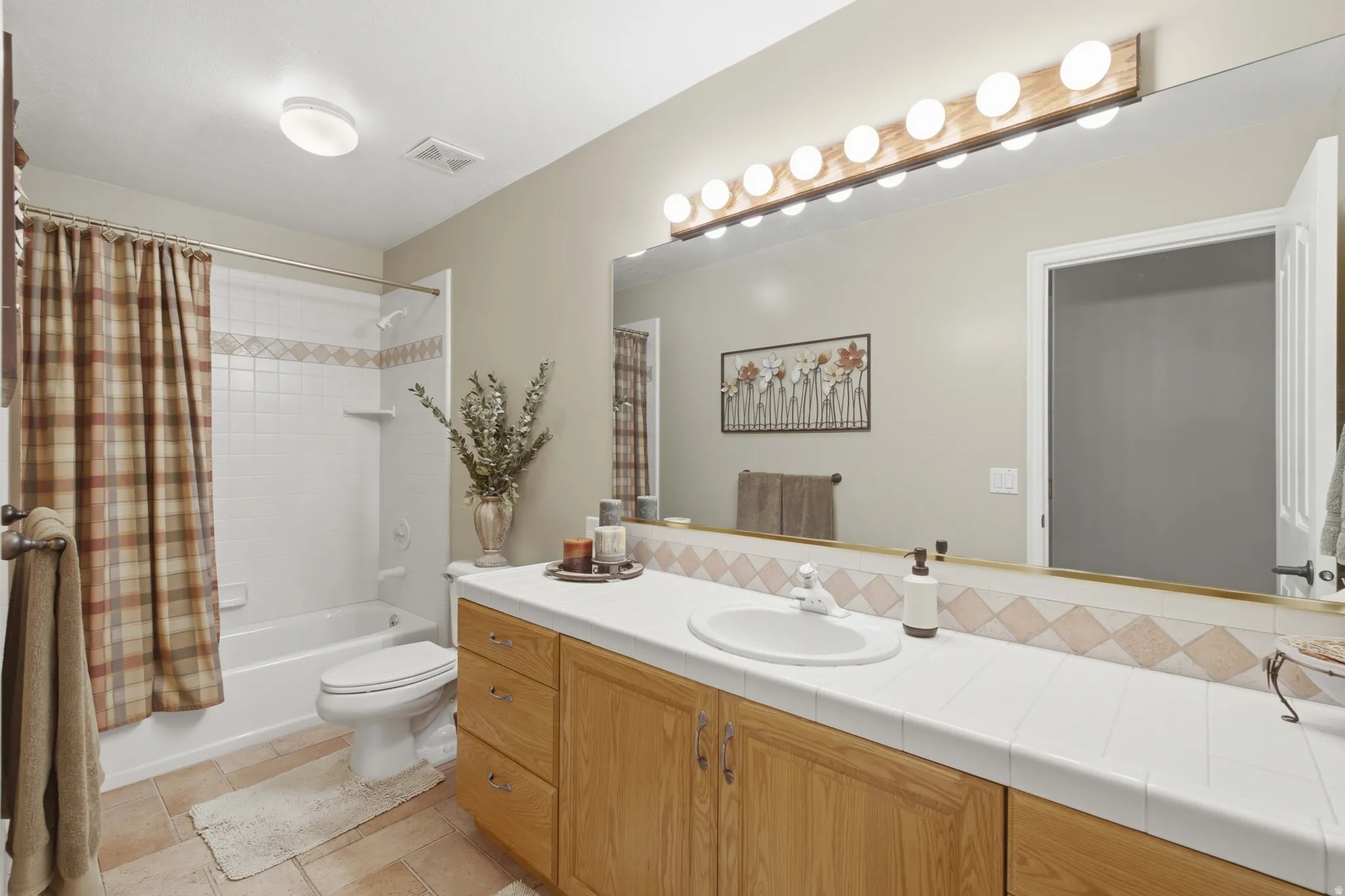 Full bathroom featuring a single vanity with wood-finish cabinetry, a white countertop, and an integrated basin