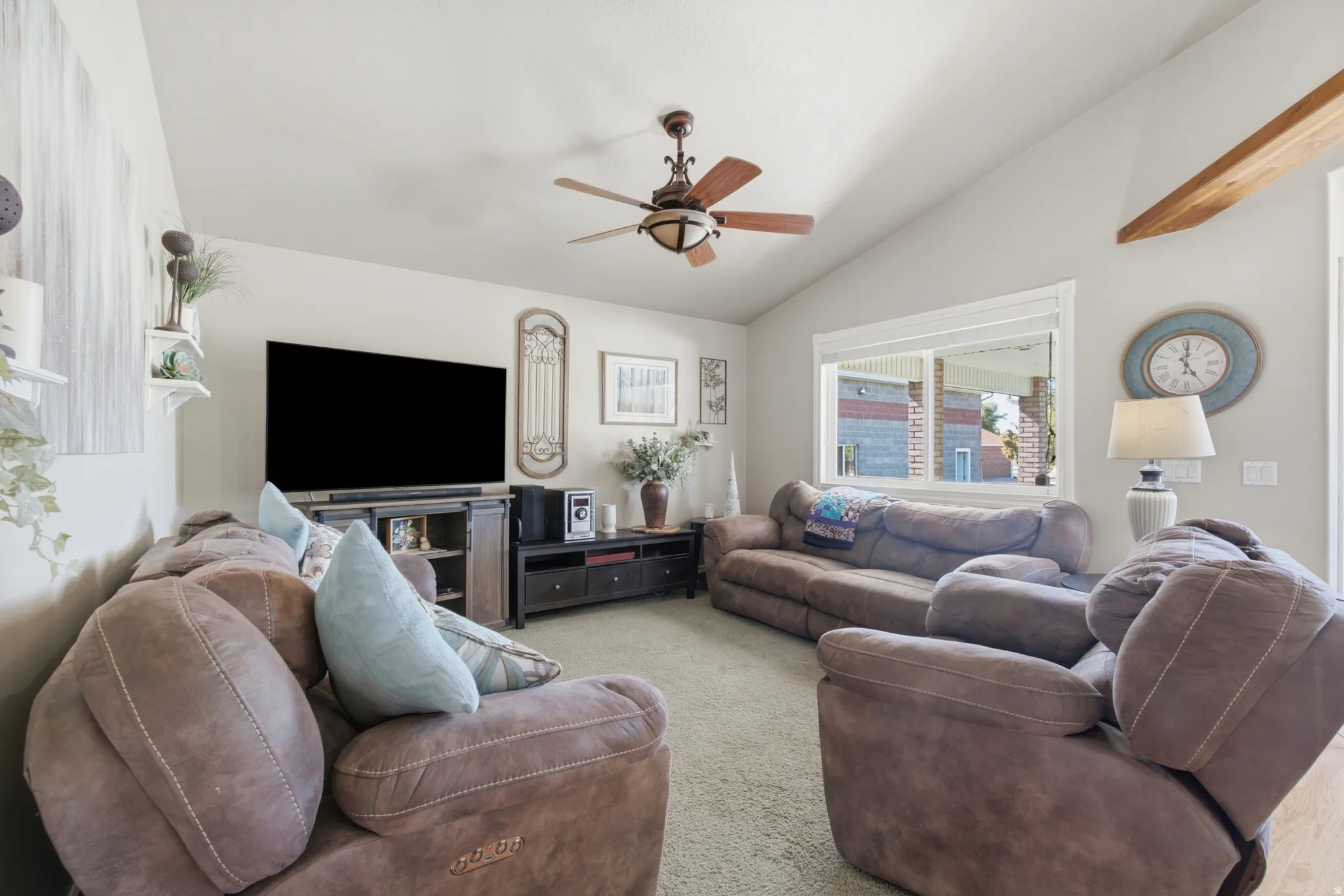 Living area featuring vaulted ceilings, a ceiling fan, and carpet flooring