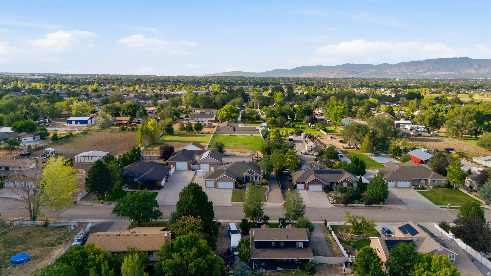Residential neighborhood featuring established homes, mature trees, mountain ranges, and open green spaces