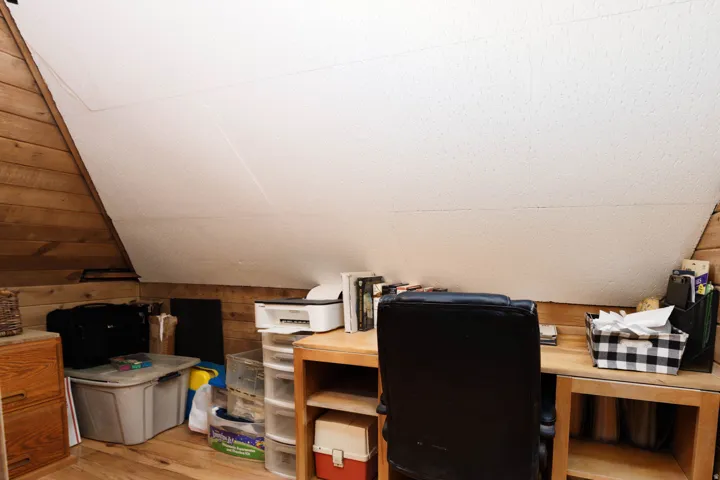 Wood-paneled walls and sloped ceilings define this space, featuring wood-finish flooring