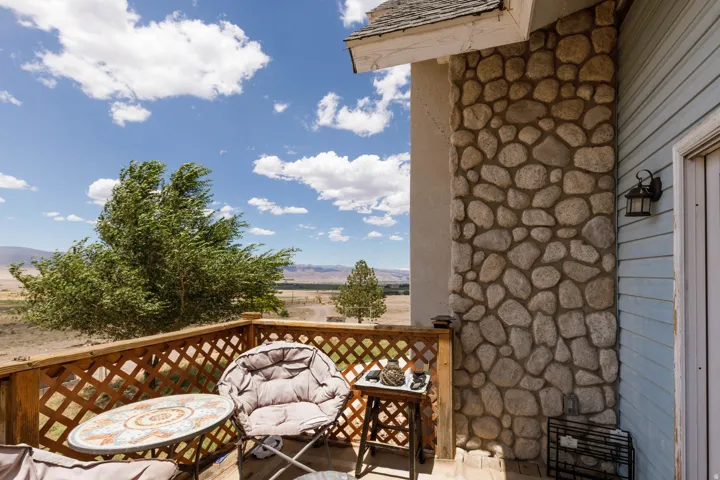 Outdoor balcony featuring a stone-clad exterior column, light blue siding, and a wooden lattice railing
