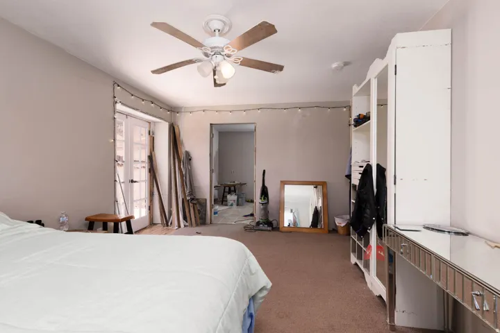 Bedroom featuring French doors, a ceiling fan with integrated lighting, and neutral wall tones