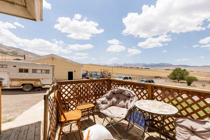Wood deck with lattice railing overlooking expansive acreage with a distant mountain backdrop