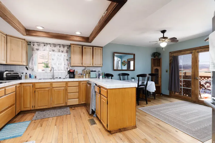 Kitchen featuring light wood cabinetry, white tiled countertops, and wood-finish flooring