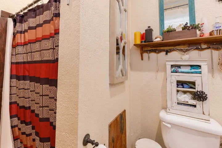 White toilet with a built-in wooden shelf and an antique-style accent mirror