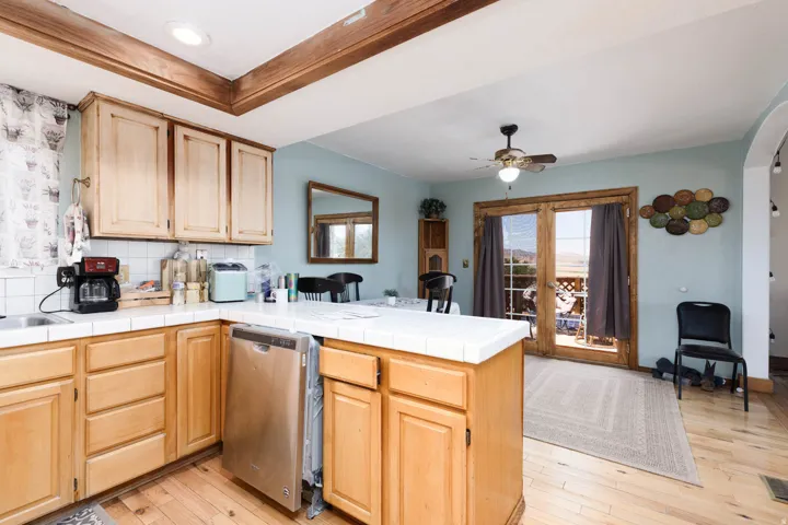 Kitchen featuring natural wood cabinetry, white tiled countertops, and a white tiled backsplash