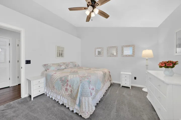Vaulted ceiling room featuring a ceiling fan with light fixture, plush gray carpeting, and light gray wall paint