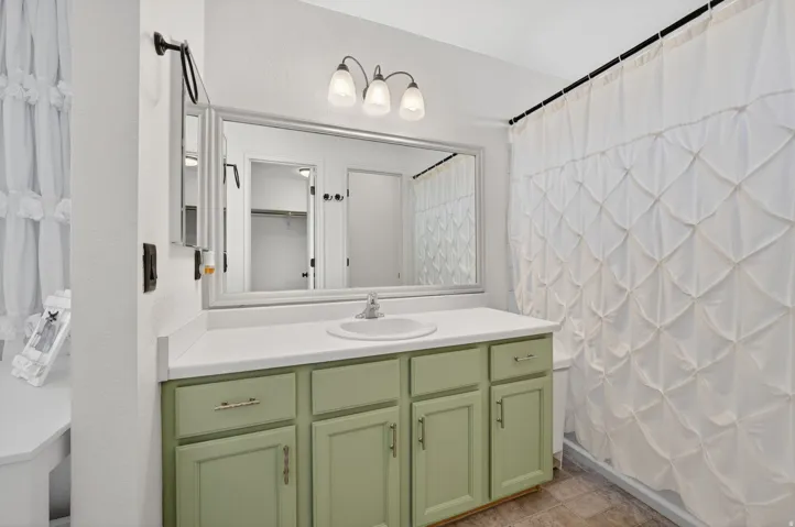 Bathroom featuring a single vanity with a mint green cabinet base, a white countertop, and a basin sink