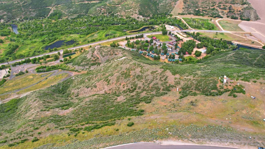 Expansive land parcel featuring natural topography, established roadways, and a developed area with multiple structures
