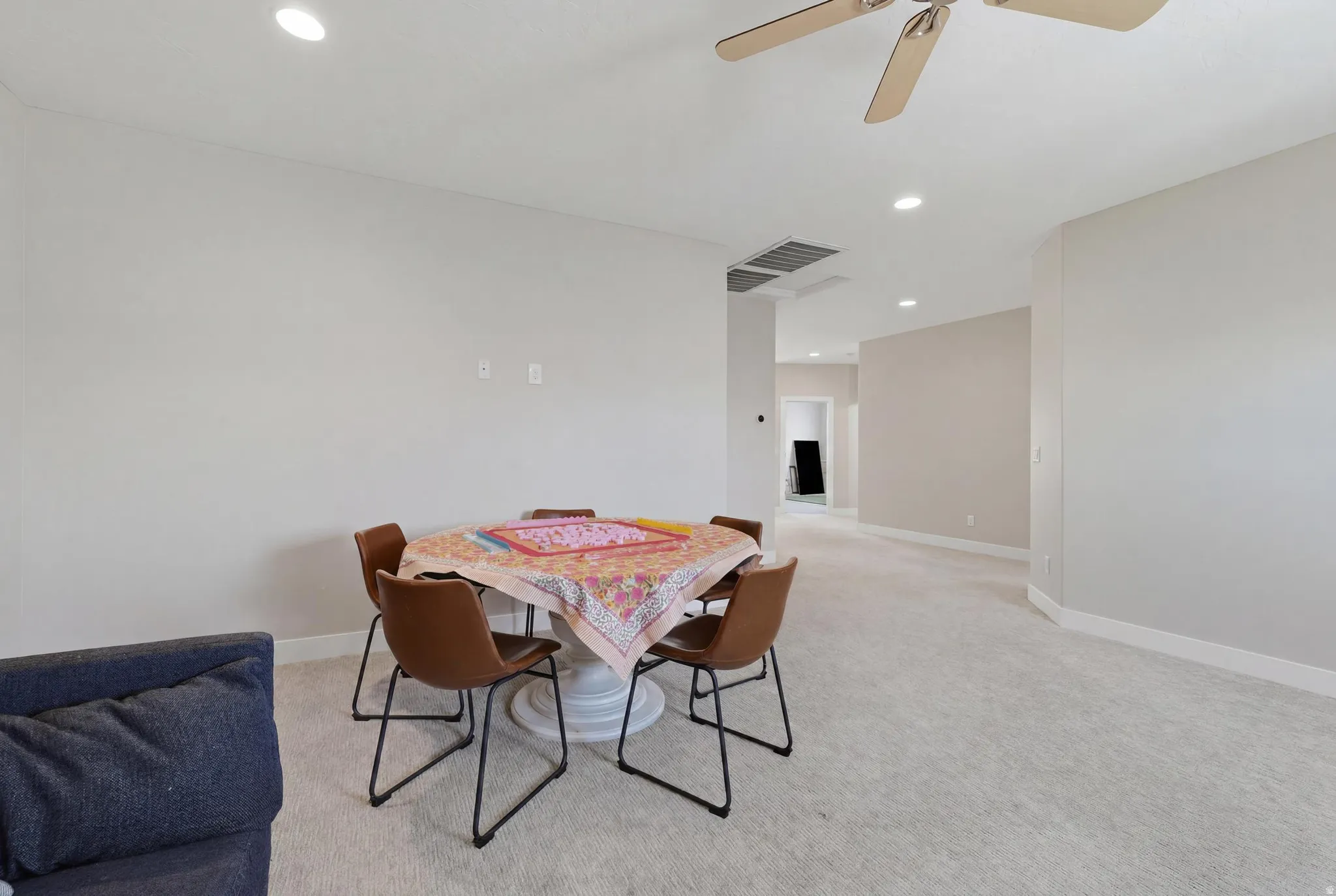 Spacious room featuring neutral carpeting, light-toned wall paint, recessed lighting, and a ceiling fan