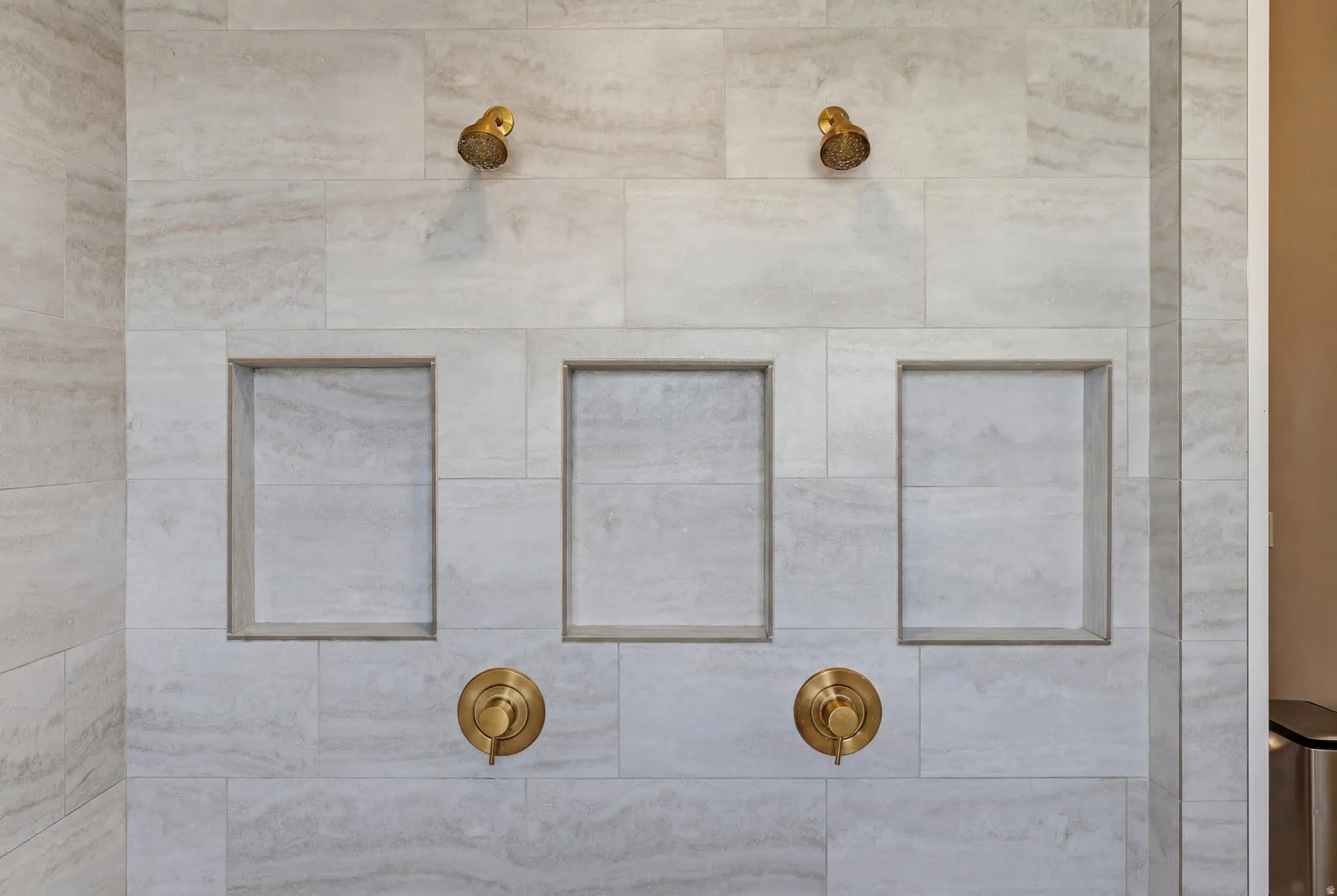 Shower surround featuring large-format tile, dual shower heads, and three recessed niches