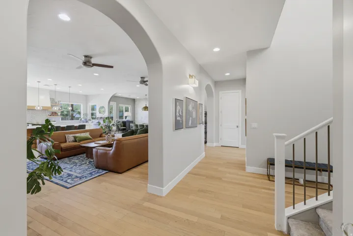 Open-concept living space featuring light wood-finish flooring, recessed lighting, and arched doorways