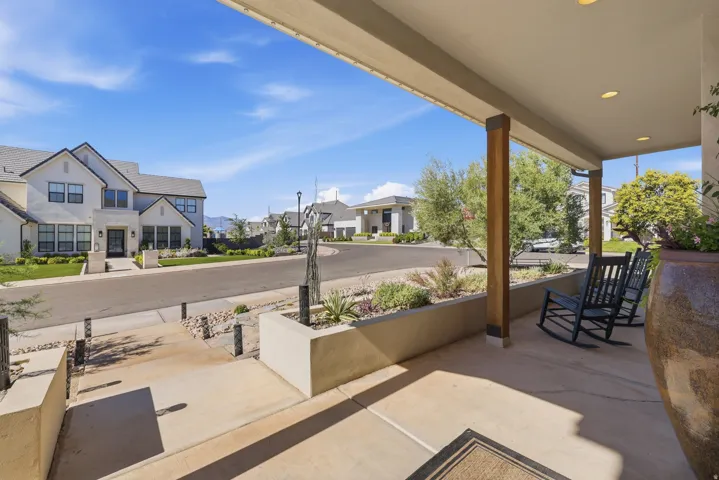 Covered front porch featuring recessed lighting, exposed wood support beams, and a concrete patio