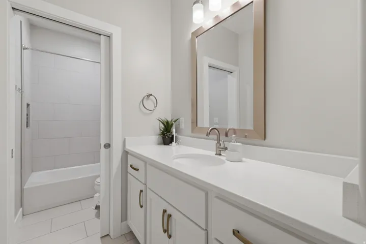 Contemporary bathroom featuring a white vanity with integrated sink, a large framed mirror, and brushed nickel fixtures
