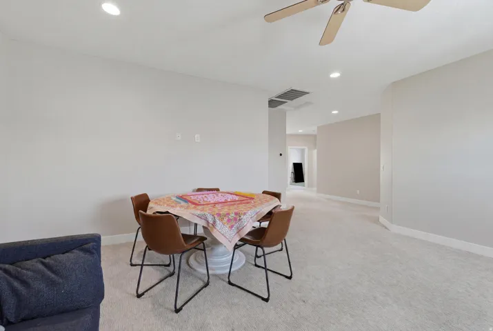 Spacious room featuring neutral carpeting, light-toned wall paint, recessed lighting, and a ceiling fan