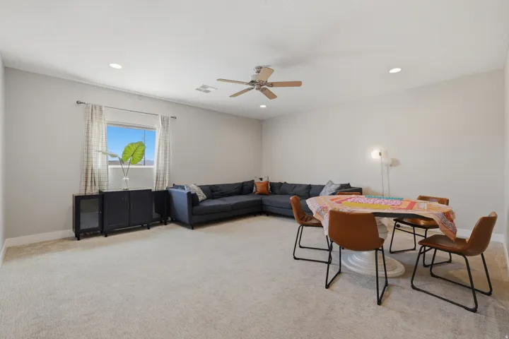 Spacious carpeted room featuring a window with patterned drapes, recessed lighting, and a ceiling fan