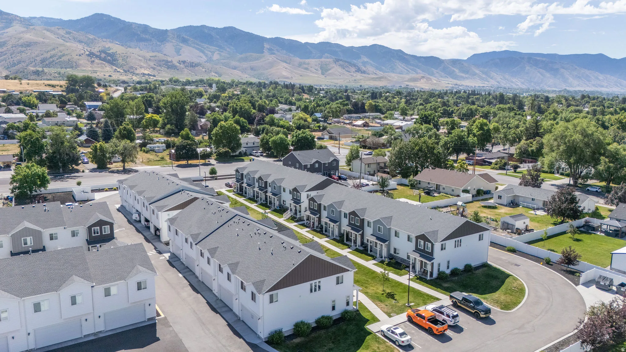 Modern townhome development featuring multiple units, paved parking areas, and manicured green spaces
